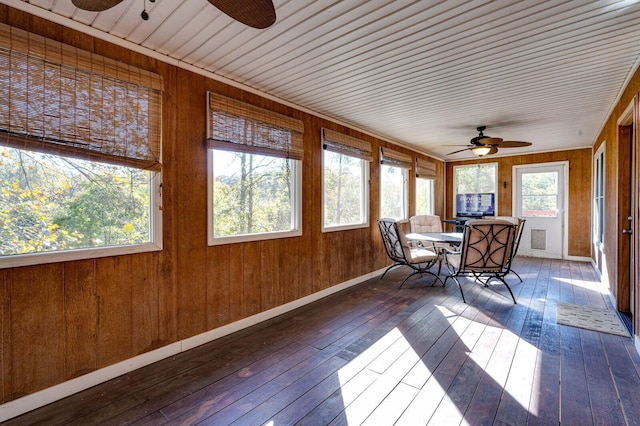 unfurnished sunroom with outdoor dining area, hardwood / wood-style flooring, wood walls, and ceiling fan