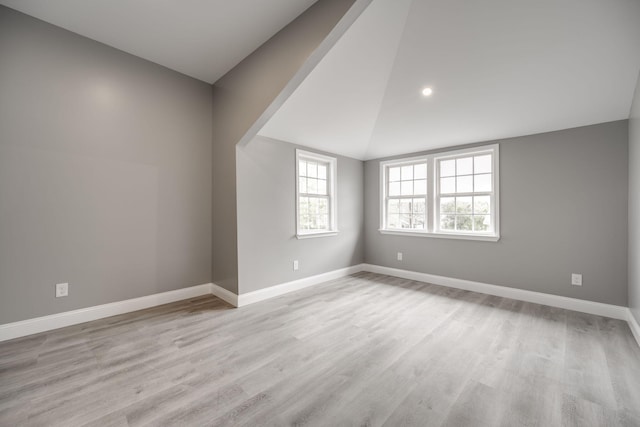 spare room featuring light hardwood / wood-style floors and lofted ceiling