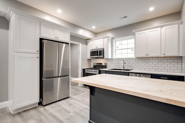 kitchen with white cabinetry, light hardwood / wood-style flooring, stainless steel appliances, and wood counters