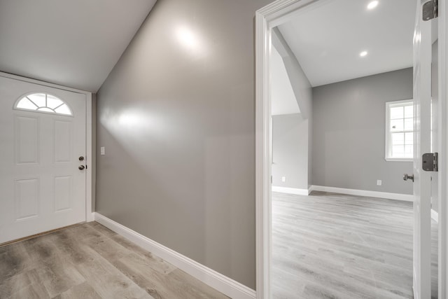 foyer featuring vaulted ceiling, a wealth of natural light, and light hardwood / wood-style flooring