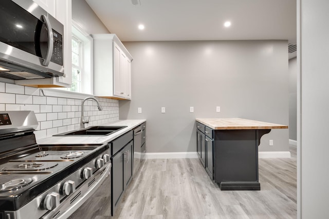 kitchen featuring appliances with stainless steel finishes, sink, light hardwood / wood-style floors, white cabinetry, and butcher block counters