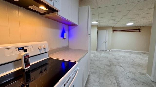 kitchen with a paneled ceiling, electric range, and white cabinets