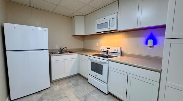 kitchen with a paneled ceiling, white cabinetry, sink, and white appliances