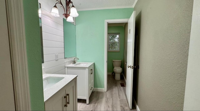 bathroom with ornamental molding, a textured ceiling, vanity, hardwood / wood-style flooring, and toilet