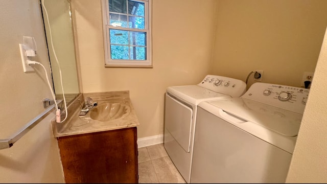 clothes washing area featuring washer and dryer, light tile patterned floors, and sink