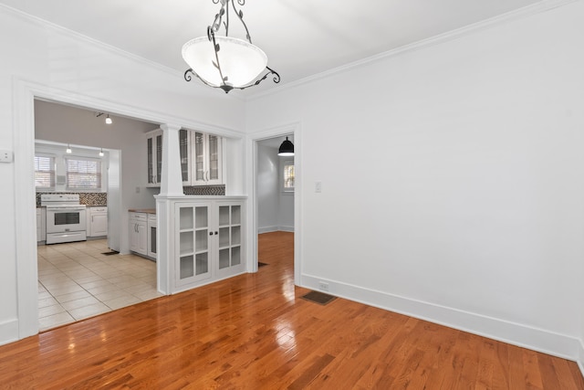 unfurnished dining area featuring light wood-type flooring and ornamental molding