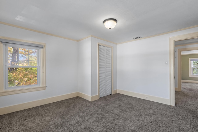 carpeted spare room featuring a healthy amount of sunlight and ornamental molding