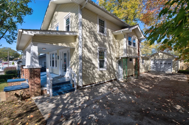 view of property exterior with covered porch, a garage, and an outbuilding