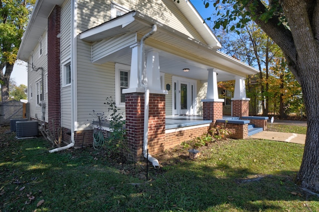 view of side of property featuring central AC unit, a porch, and a lawn