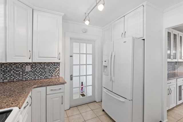 kitchen featuring ornamental molding, dark stone countertops, range, white cabinetry, and white fridge with ice dispenser