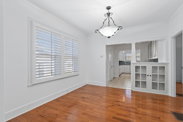 unfurnished dining area with crown molding and light hardwood / wood-style flooring