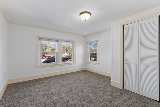 unfurnished bedroom featuring dark colored carpet, a closet, and ornamental molding