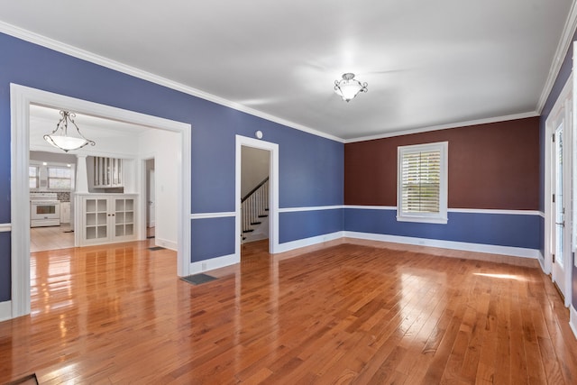 empty room with ornamental molding and light wood-type flooring