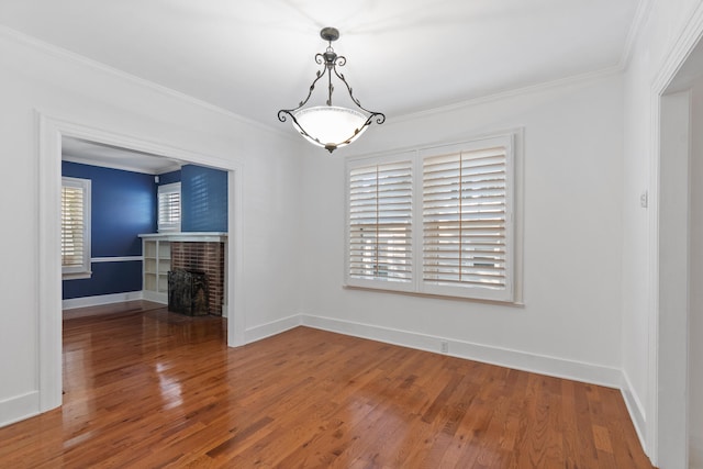 unfurnished dining area featuring hardwood / wood-style flooring, ornamental molding, and a brick fireplace