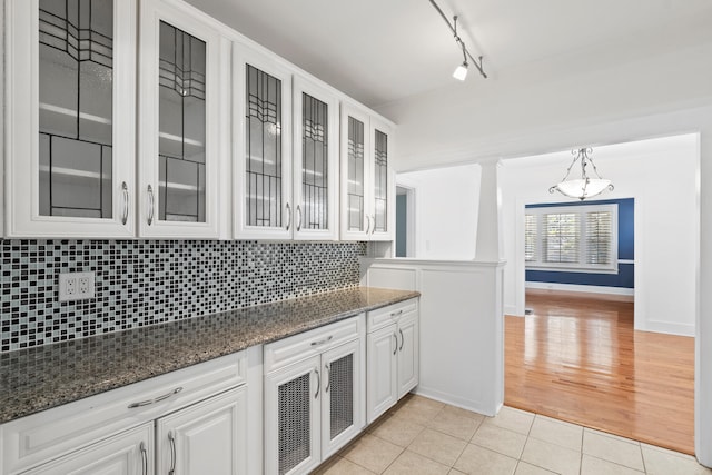 kitchen featuring backsplash, pendant lighting, track lighting, white cabinets, and light wood-type flooring