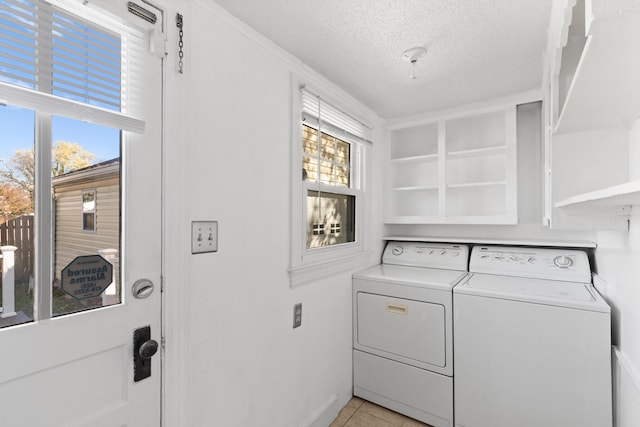 laundry area with washing machine and dryer, plenty of natural light, light tile patterned floors, and a textured ceiling