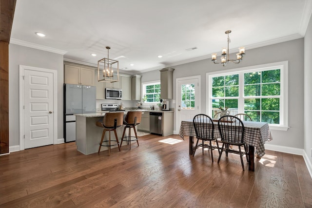 kitchen with appliances with stainless steel finishes, a chandelier, gray cabinetry, a center island, and dark wood-style flooring