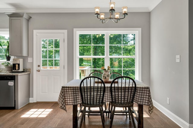 dining area featuring crown molding, a chandelier, baseboards, and wood finished floors