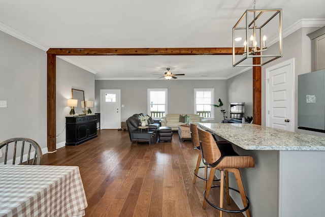kitchen with dark wood finished floors, light stone countertops, a kitchen breakfast bar, a chandelier, and decorative light fixtures