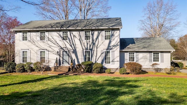 colonial house featuring a shingled roof and a front lawn