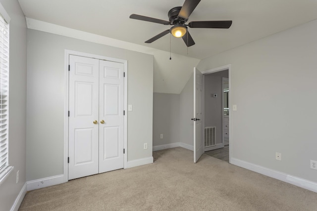 unfurnished bedroom with visible vents, light carpet, lofted ceiling, and baseboards