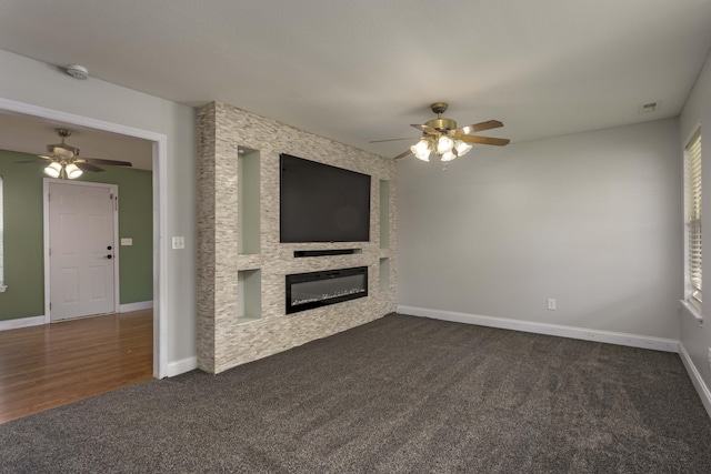 unfurnished living room with dark colored carpet, baseboards, a large fireplace, and visible vents