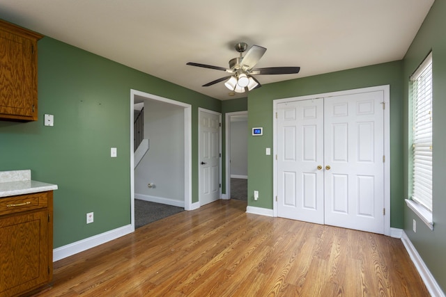 unfurnished bedroom featuring a closet, ceiling fan, light wood-type flooring, and baseboards