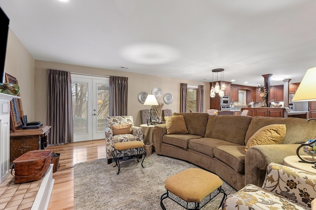 living room with french doors, light wood-type flooring, and an inviting chandelier