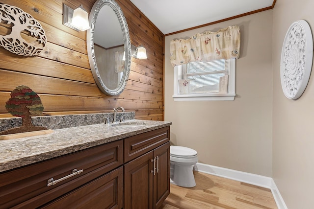 bathroom with hardwood / wood-style floors, vanity, wood walls, crown molding, and toilet