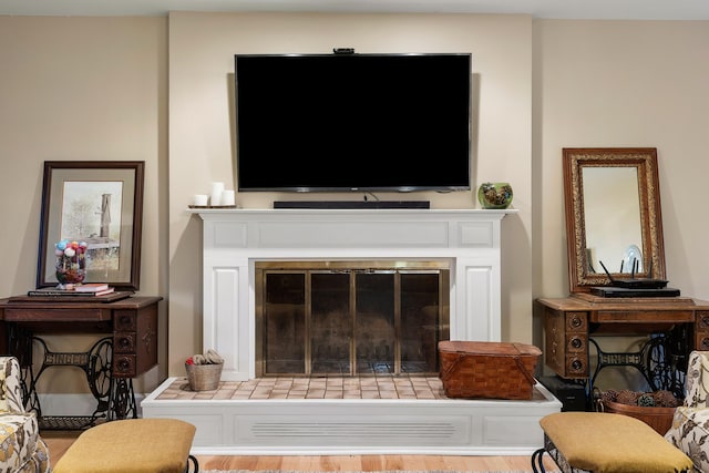 living room featuring wood-type flooring and a tiled fireplace