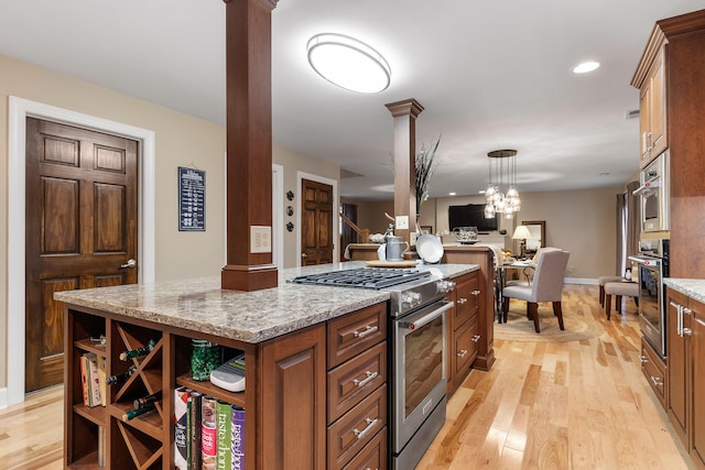 kitchen featuring hanging light fixtures, light hardwood / wood-style flooring, a kitchen island, light stone counters, and stainless steel appliances