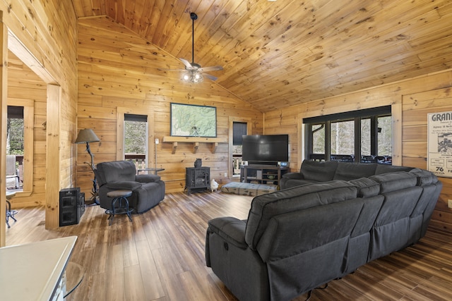 living room featuring wood ceiling, wood walls, a healthy amount of sunlight, and a wood stove