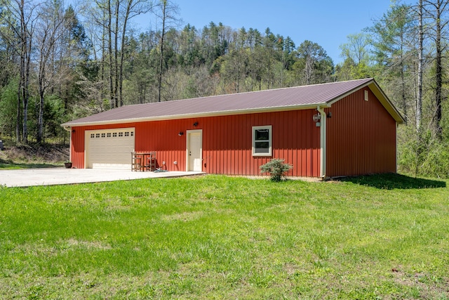 exterior space with an outdoor structure, a garage, driveway, and a forest view