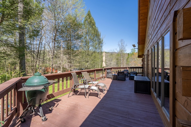 wooden deck with an outdoor hangout area and a grill