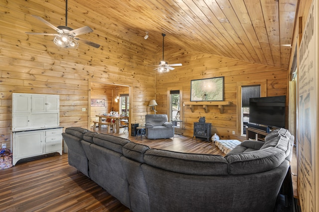 living area with a ceiling fan, vaulted ceiling, a wood stove, dark wood finished floors, and wooden walls