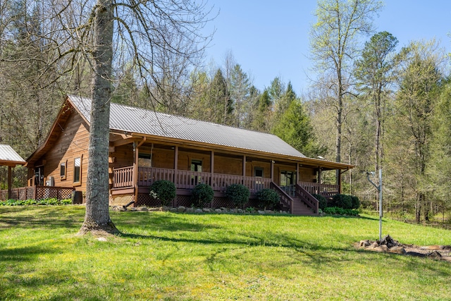 view of front of home featuring a view of trees, a porch, metal roof, and a front yard