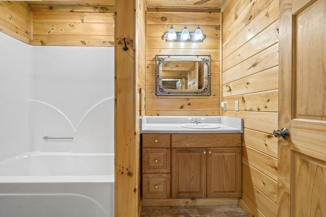 full bath featuring wooden walls, vanity, and a tub to relax in