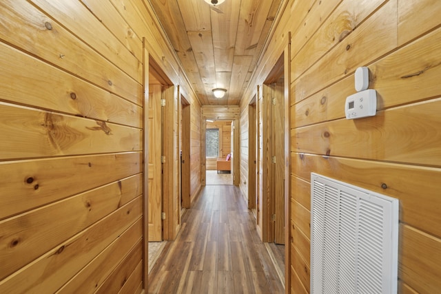 corridor with visible vents, wood ceiling, wooden walls, and hardwood / wood-style floors