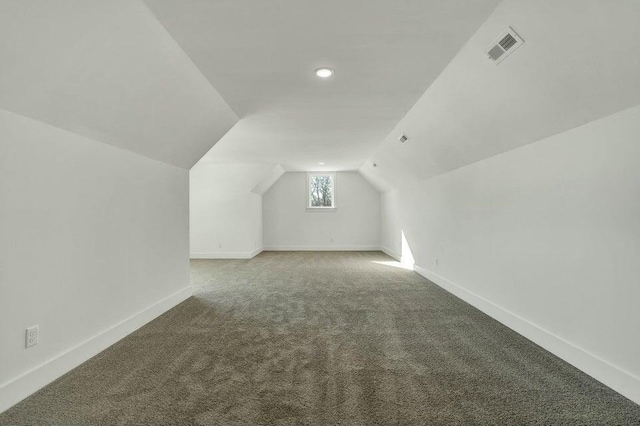 additional living space with carpet, visible vents, baseboards, and vaulted ceiling