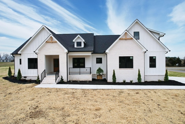 modern farmhouse with covered porch, board and batten siding, and brick siding