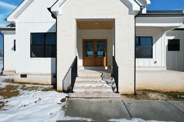 snow covered property entrance with french doors