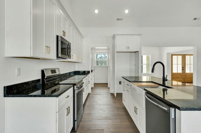 kitchen with stainless steel appliances, dark stone counters, and white cabinets