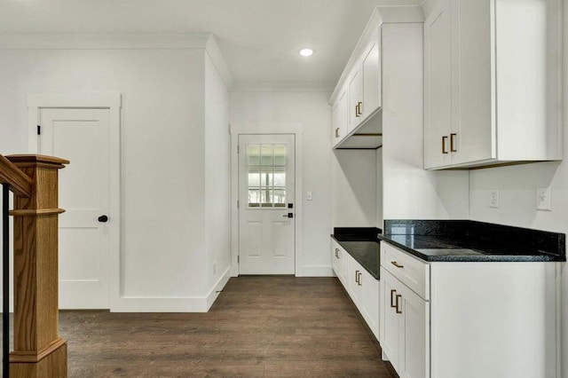 kitchen featuring crown molding, dark stone countertops, dark hardwood / wood-style flooring, and white cabinets