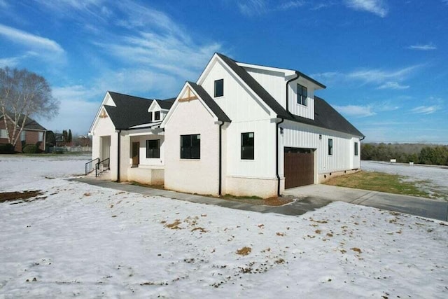 snow covered back of property featuring a garage