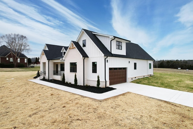 view of front of house featuring board and batten siding, a front yard, concrete driveway, and a shingled roof