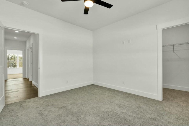 unfurnished bedroom featuring lofted ceiling, ceiling fan, carpet, a spacious closet, and a closet