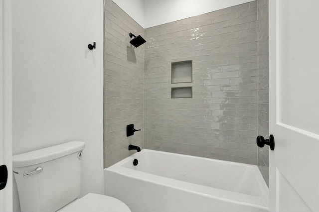 bathroom featuring tiled shower / bath combo and toilet