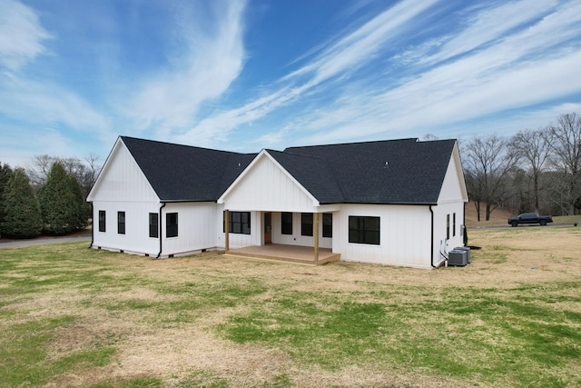back of property with a shingled roof and a lawn