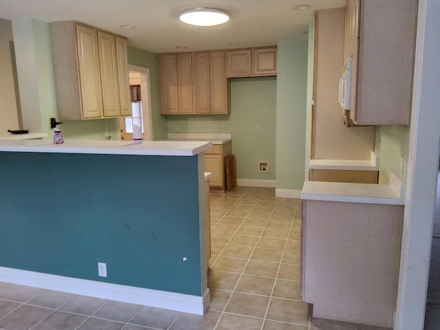 kitchen with kitchen peninsula, light brown cabinetry, light tile patterned floors, and white refrigerator