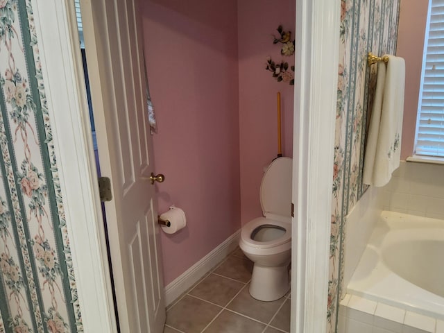 bathroom with tile patterned floors, a relaxing tiled tub, and toilet